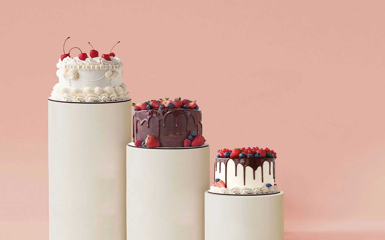 Three decorated cakes arranged on descending tiers.
